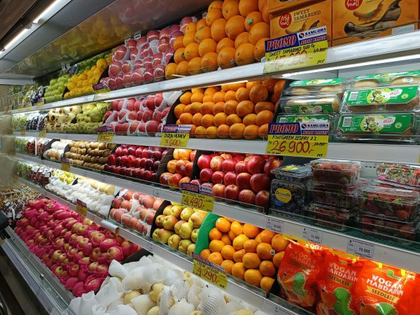 A refrigerated display case is stocked with fresh fruits.